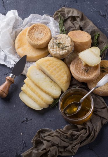 Traditional Portugese semi-soft cheeses from evora alentejo region served with fresh rosemary and honey. Top View. Copy Space